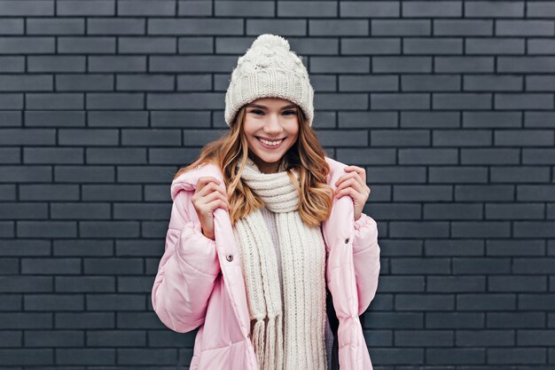 Sensuelle jeune femme de bonne humeur se promenant par temps froid. Portrait en plein air d'agréable fille blonde posant en bonnet tricoté.