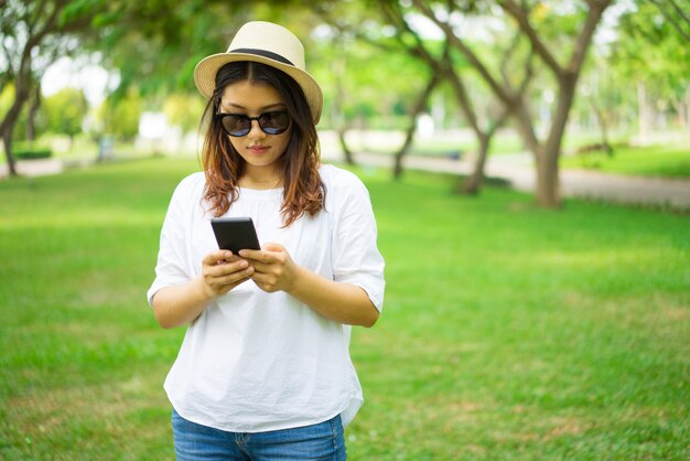 Sérieuse femme asiatique concentrée vérifiant message sur smartphone