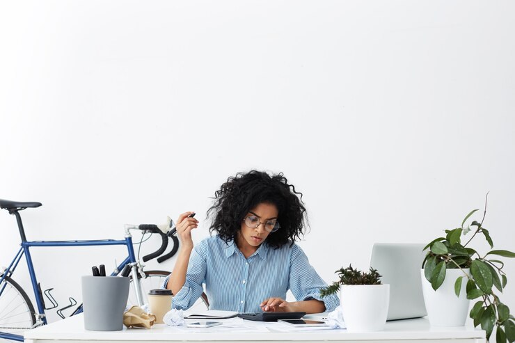 Photo gratuit sérieuse jeune femme comptable métisse travaillant sur le rapport financier