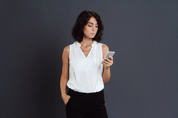 Sérieusement jeune femme tenant son téléphone dans les mains