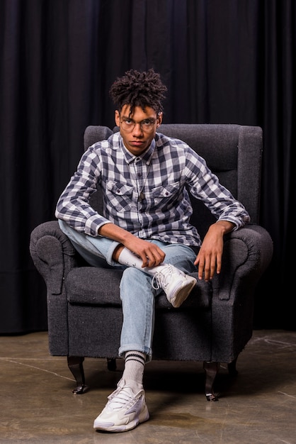 Sérieux, beau, jeune homme africain, séance fauteuil, regarder appareil-photo