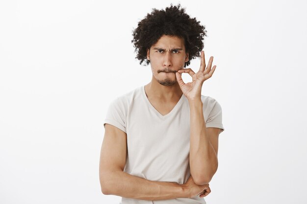 Sérieux bel homme promet de ne pas parler, fermant la bouche sur le sceau