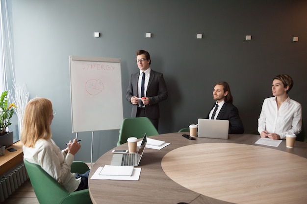 Sérieux entraîneur masculin faisant une présentation sur un tableau à feuilles mobiles à des collègues de travail