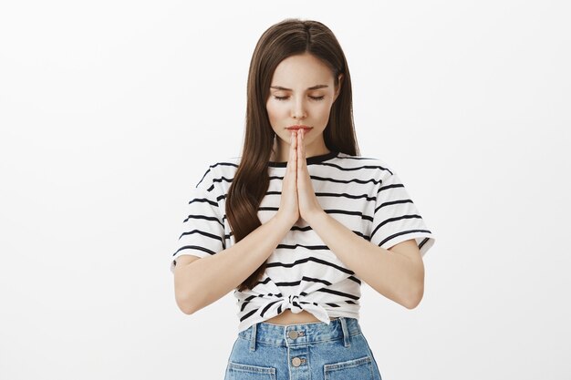 Sérieux espoir jeune femme brune demandant à Dieu, plaidant ou souhaitant, priant