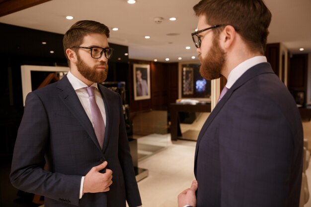 Photo gratuite sérieux jeune homme d'affaires barbu debout à l'intérieur