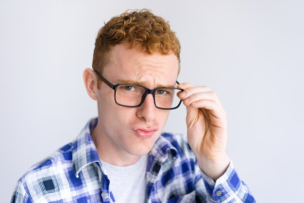 Sérieux, jeune homme, froncer les sourcils et ajustement lunettes