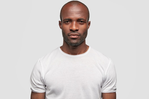 Sérieux jeune homme à la peau sombre regarde avec une expression sûre à la caméra