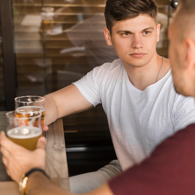 Sérieux jeune homme avec ses amis, boire de la bière