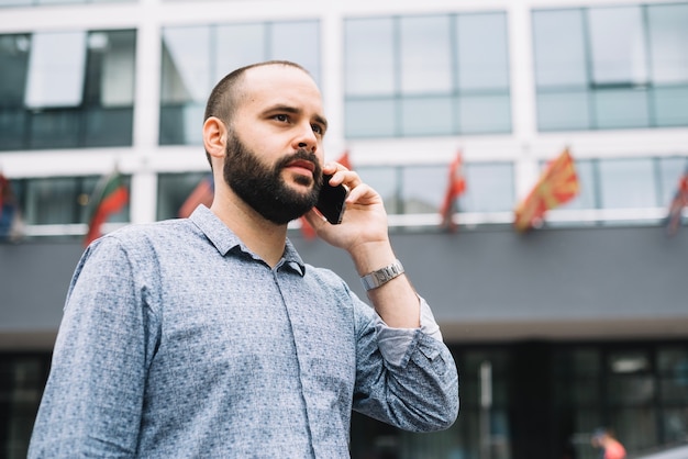 Sérieux jeune homme avec smartphone à la rue