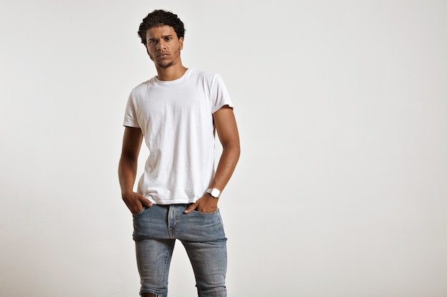 Photo gratuite sérieux jeune mannequin afro-américain athlétique avec les mains dans les poches de son jean bleu serré portant un t-shirt blanc