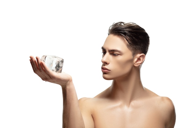 Sérieux. Portrait de jeune homme isolé sur fond de studio blanc. Modèle masculin attrayant de race blanche. Concept de mode et de beauté, soins personnels, soins du corps et de la peau. Beau garçon avec une peau bien entretenue.