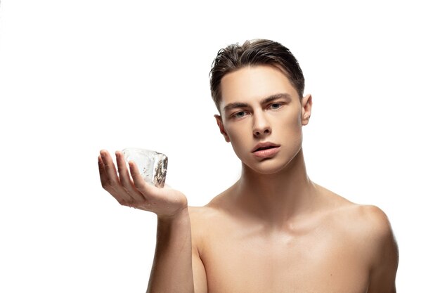 Sérieux. Portrait de jeune homme isolé sur fond de studio blanc. Modèle masculin attrayant de race blanche. Concept de mode et de beauté, soins personnels, soins du corps et de la peau. Beau garçon avec une peau bien entretenue.