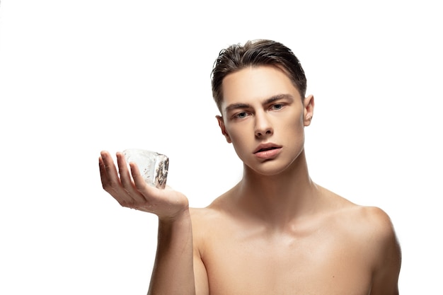 Sérieux. Portrait de jeune homme isolé sur fond de studio blanc. Modèle masculin attrayant de race blanche. Concept de mode et de beauté, soins personnels, soins du corps et de la peau. Beau garçon avec une peau bien entretenue.