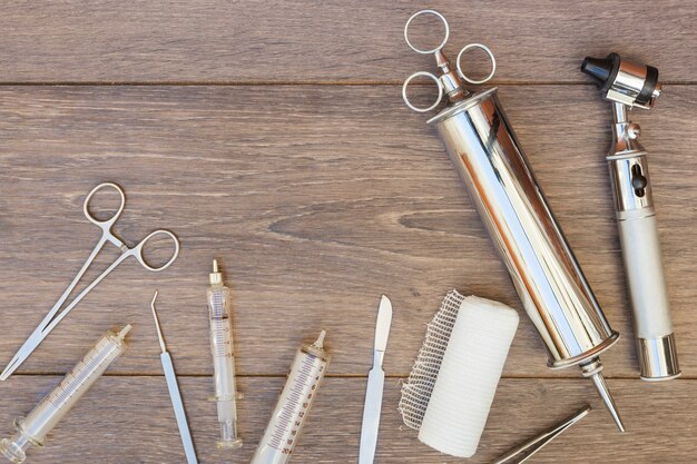 Seringue vintage en acier inoxydable; otoscope et équipement médical sur un bureau en bois