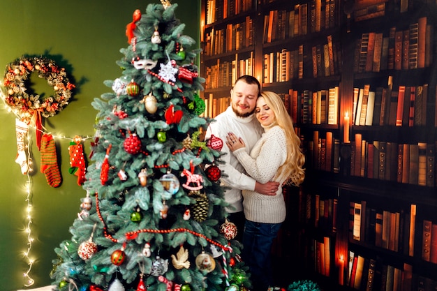 Serrant le couple se tient devant un arbre de Noël