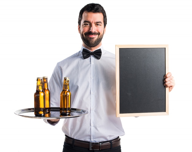 Photo gratuite serveur avec des bouteilles de bière sur le plateau tenant une pancarte vide