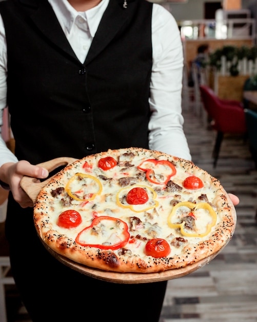 Serveur Détient Une Pizza à La Viande Avec Des Poivrons Rouges Jaunes Tomate Et Fromage