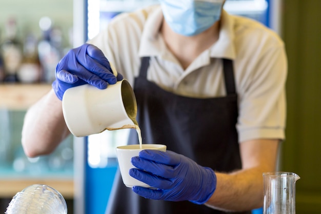 Serveur de gros plan avec des gants, préparer le café
