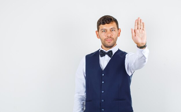 Serveur montrant assez de geste et souriant en chemise, vue de face du gilet.