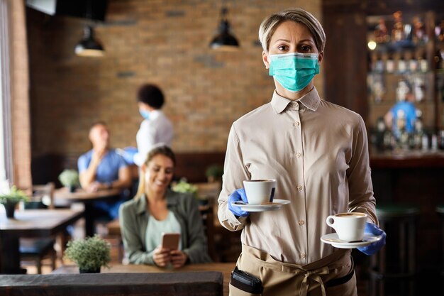 Serveuse avec masque protecteur et gants servant du café dans un café