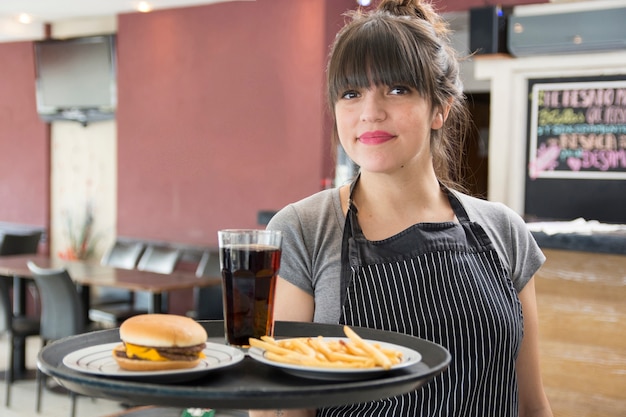 Serveuse tenant un plateau de cocktail; burger au poulet et frites