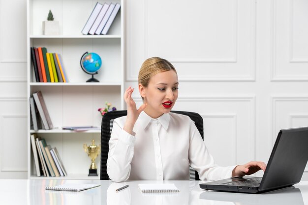 Service client jolie fille en chemise blanche avec rouge à lèvres et ordinateur portable irrité pendant le travail