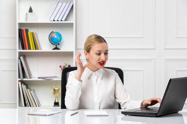 Service client jolie fille en chemise blanche avec rouge à lèvres et ordinateur portable irrité pendant le travail