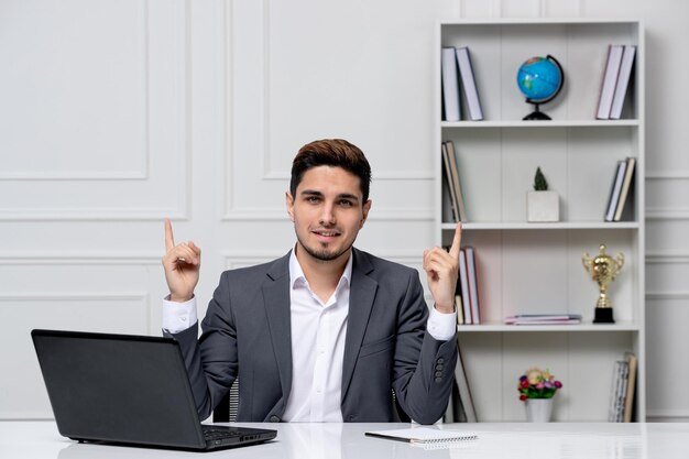 Service client mignon beau mec en costume de bureau avec ordinateur heureux pour l'achèvement de la tâche