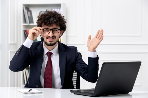 Service à la clientèle beau jeune homme en costume de bureau avec ordinateur portable et casque souriant dans des verres