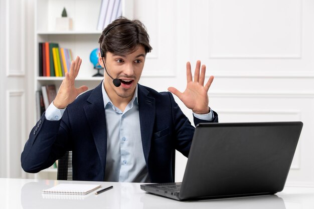 Service à la clientèle beau mec avec casque et ordinateur portable en costume excité en agitant les mains