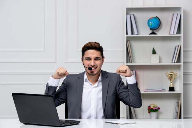 Service à la clientèle beau mec intelligent avec ordinateur portable en blazer de bureau gris très excité pour le travail