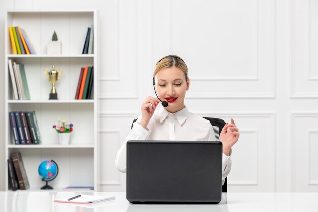 Service à la clientèle jolie femme en chemise blanche avec casque et ordinateur parlant à l'appel