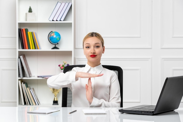 Service à la clientèle jolie fille en chemise blanche avec rouge à lèvres et ordinateur portable montrant le geste de finition