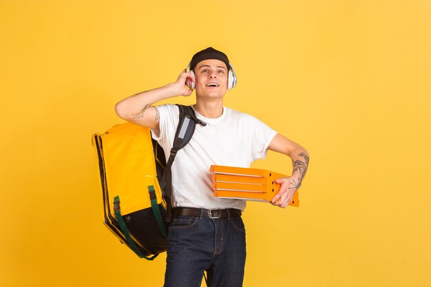 Service de livraison sans contact pendant la quarantaine l'homme livre de la nourriture et des sacs à provisions pendant les émotions d'isolation du livreur isolé sur un mur jaune