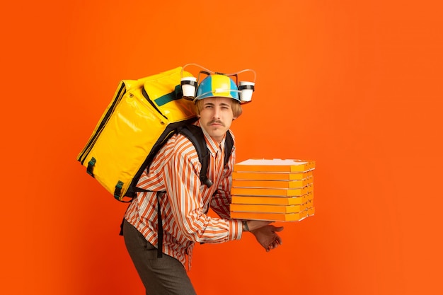 Service de livraison sans contact pendant la quarantaine. L'homme livre de la nourriture et des sacs à provisions pendant l'isolation. Émotions de livreur isolé sur fond orange.