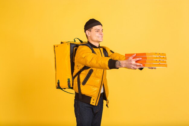 Service de livraison sans contact pendant la quarantaine. L'homme livre de la nourriture et des sacs à provisions pendant l'isolation. Émotions de livreur isolé sur jaune