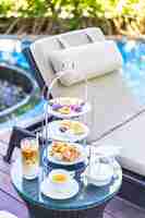 Photo gratuite service à thé l'après-midi avec café au lait et thé chaud sur la table près de la chaise autour de la piscine