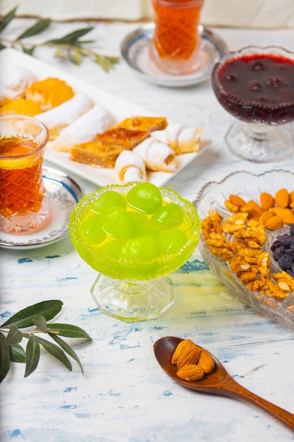 Service à thé avec des variétés de noix traditionnelles, citron, confiture et bonbons servis sur une nappe blanche