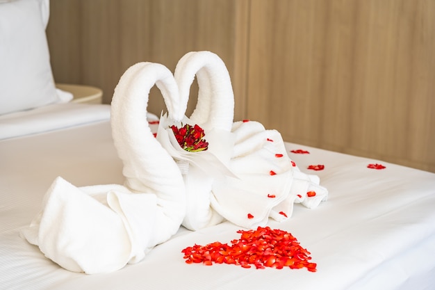 Serviette de cygne sur le lit avec des pétales de fleurs de rose rouge