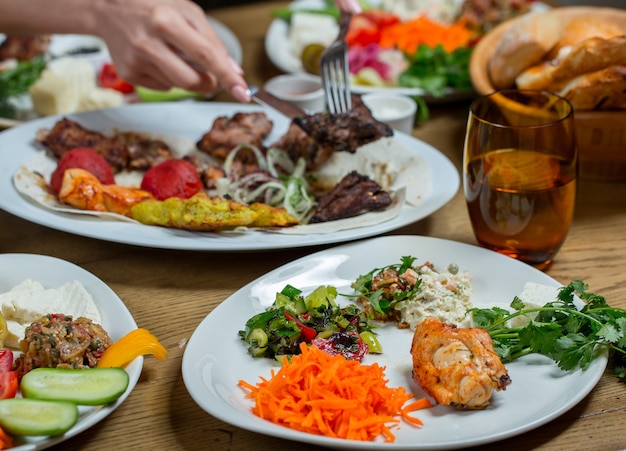 Set de dîner dans des assiettes blanches contenant de la viande et des légumes, des collations et des aliments.