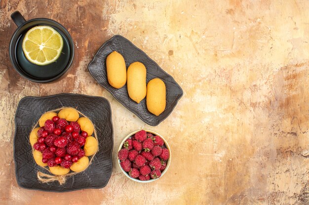 Set de table avec un gâteau cadeau aux framboises et une tasse de thé au citron sur table de couleurs mélangées