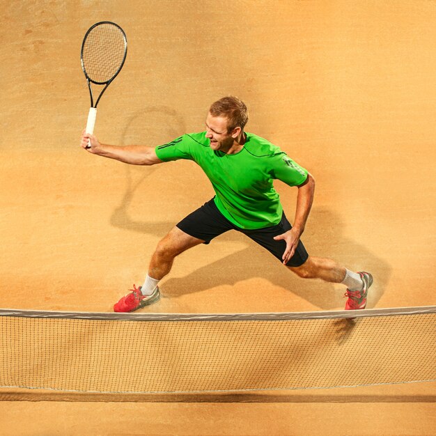 Le seul joueur de saut, homme en forme de race blanche, jouant au tennis sur le court de terre