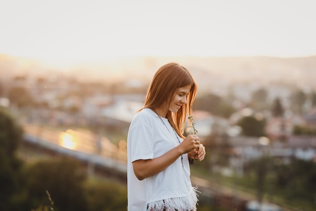 Seule femme en chemise blanche se dresse avec une fleur de champ