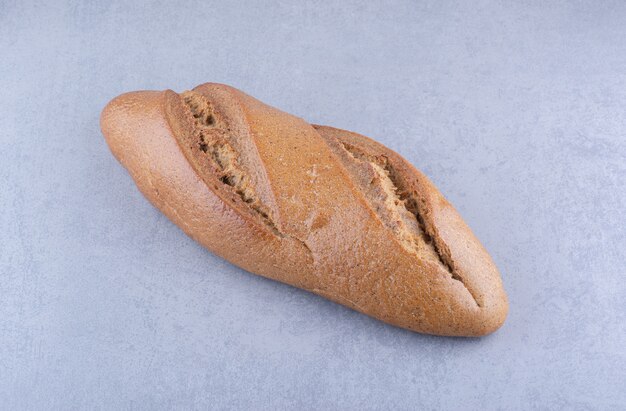 Une seule miche de pain bâton sur une surface en marbre
