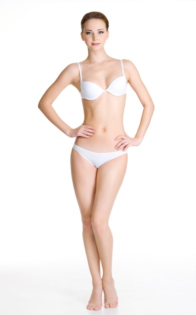Sexy jeune femme mince avec un beau corps parfait posant sur un espace blanc. Portrait en pied