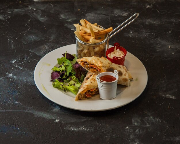 Shaurma arabe servi avec frites, sauce et salade verte.