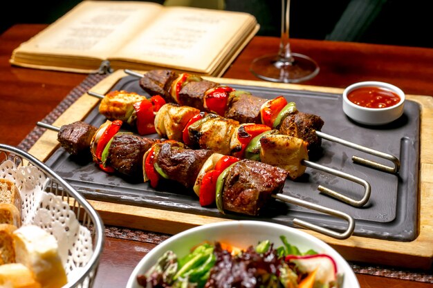 Shish kebab aux poivrons colorés servis avec du ketchup et des légumes frais