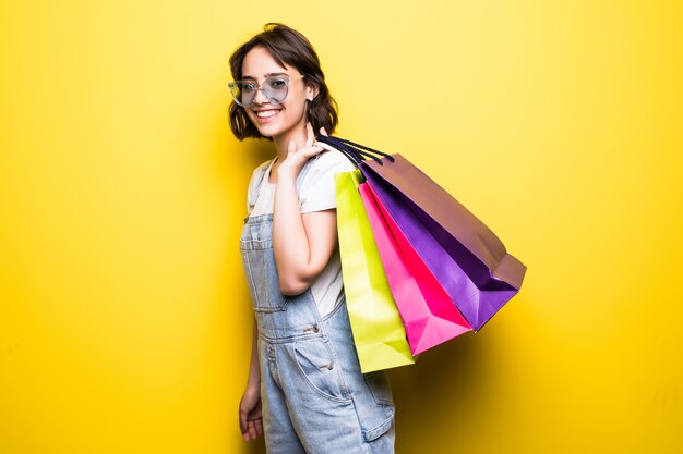 Shopping heureuse jeune femme à lunettes de soleil tenant des sacs.