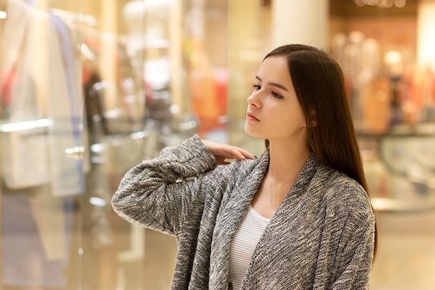 Shopping une jeune fille regarde les vitrines sourit fait des achats dans un centre commercial