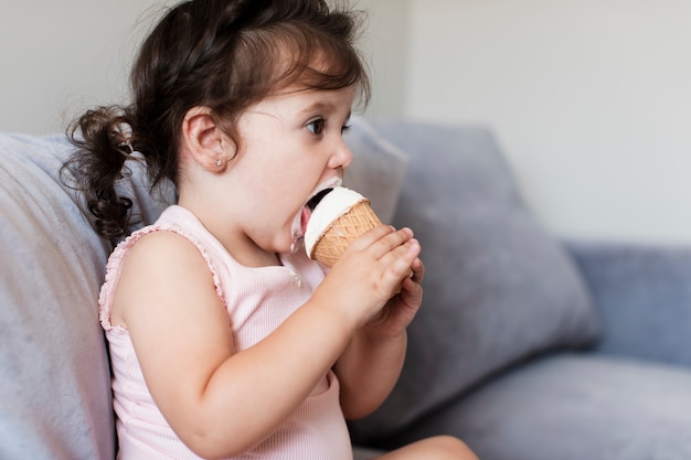 Photo gratuite sideview, bébé fille, manger, glace